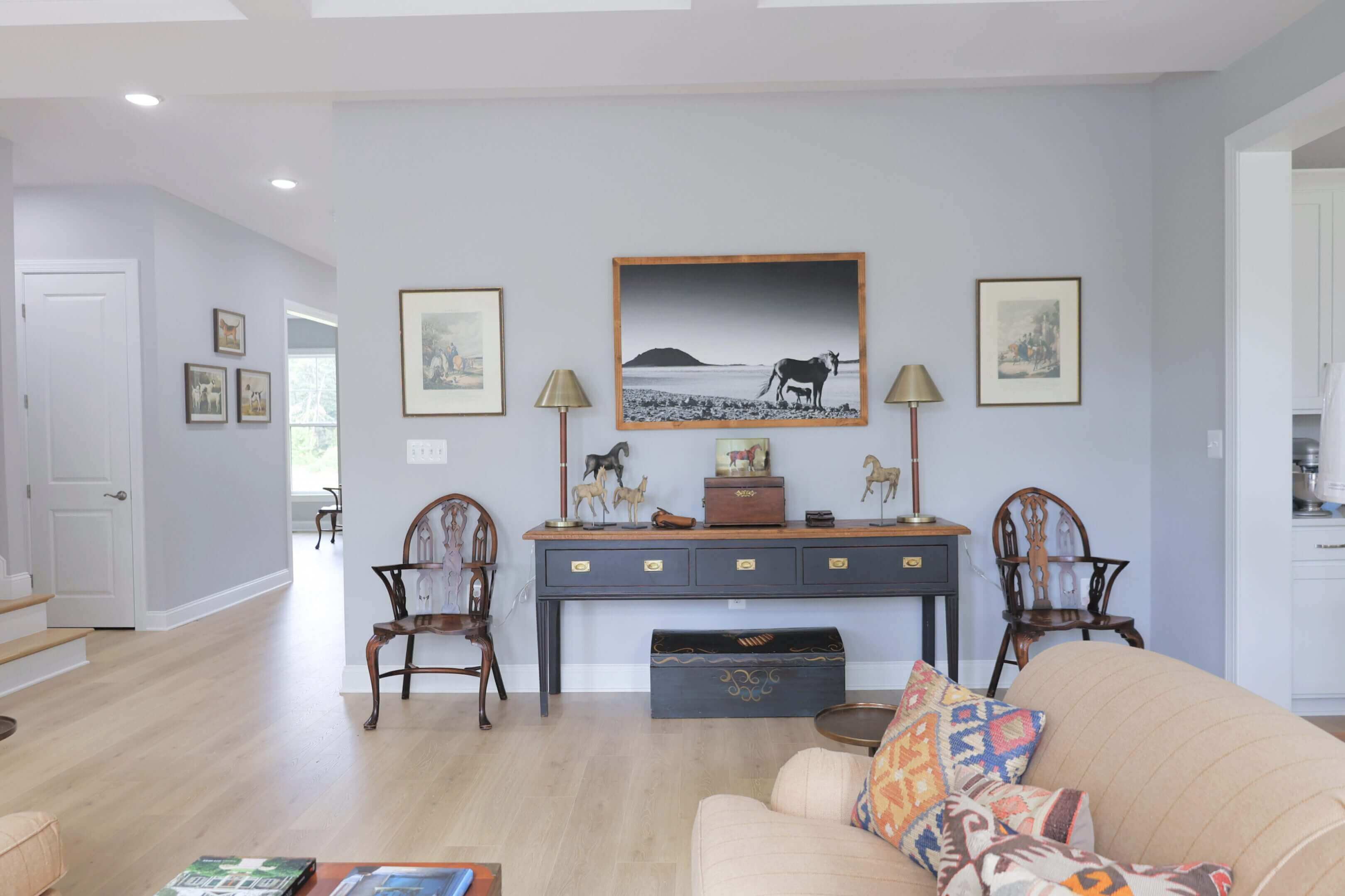 Elegant living room with vintage chairs, a wooden console, and framed art on light gray walls.