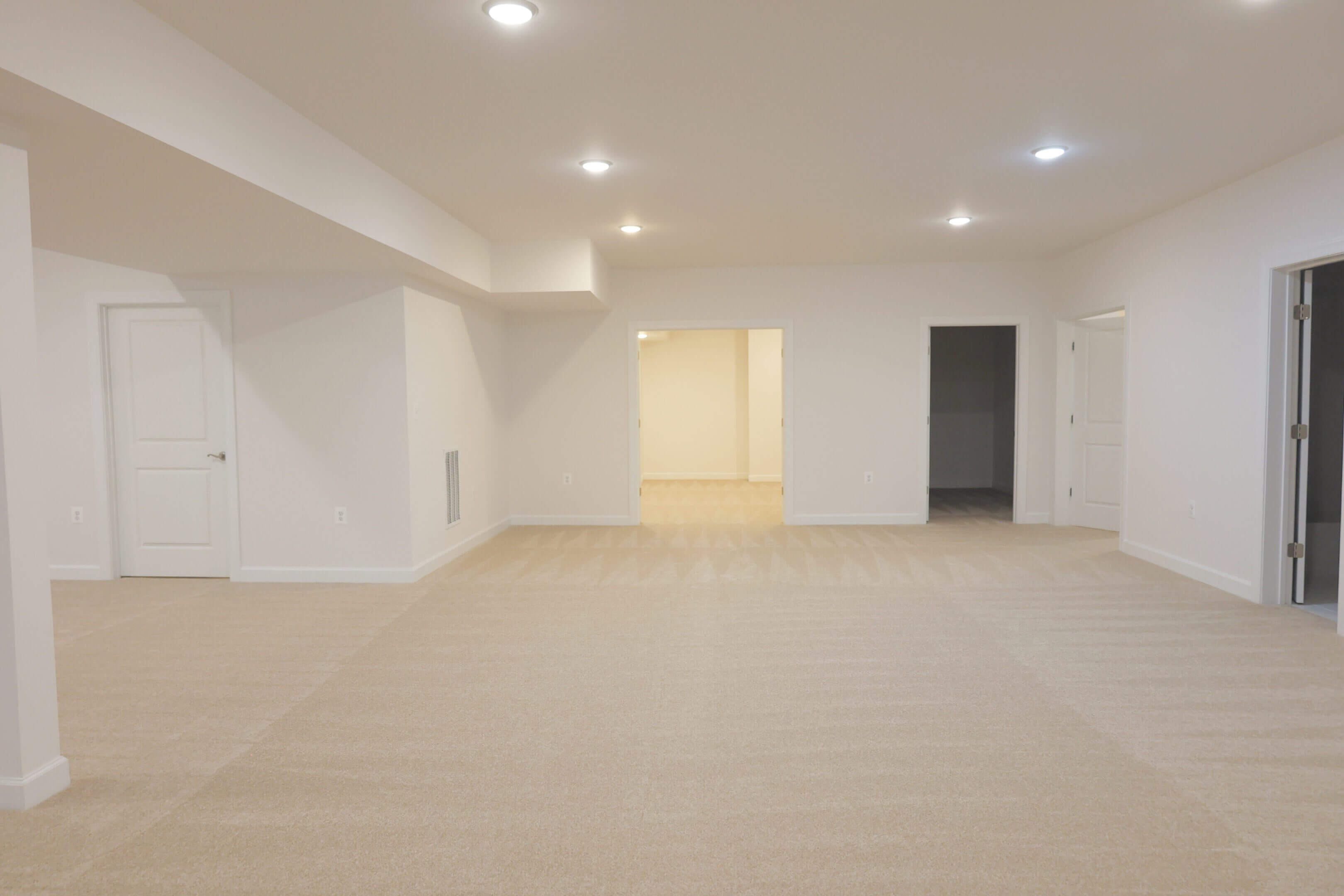Empty, spacious room with neutral colors and recessed lighting.
