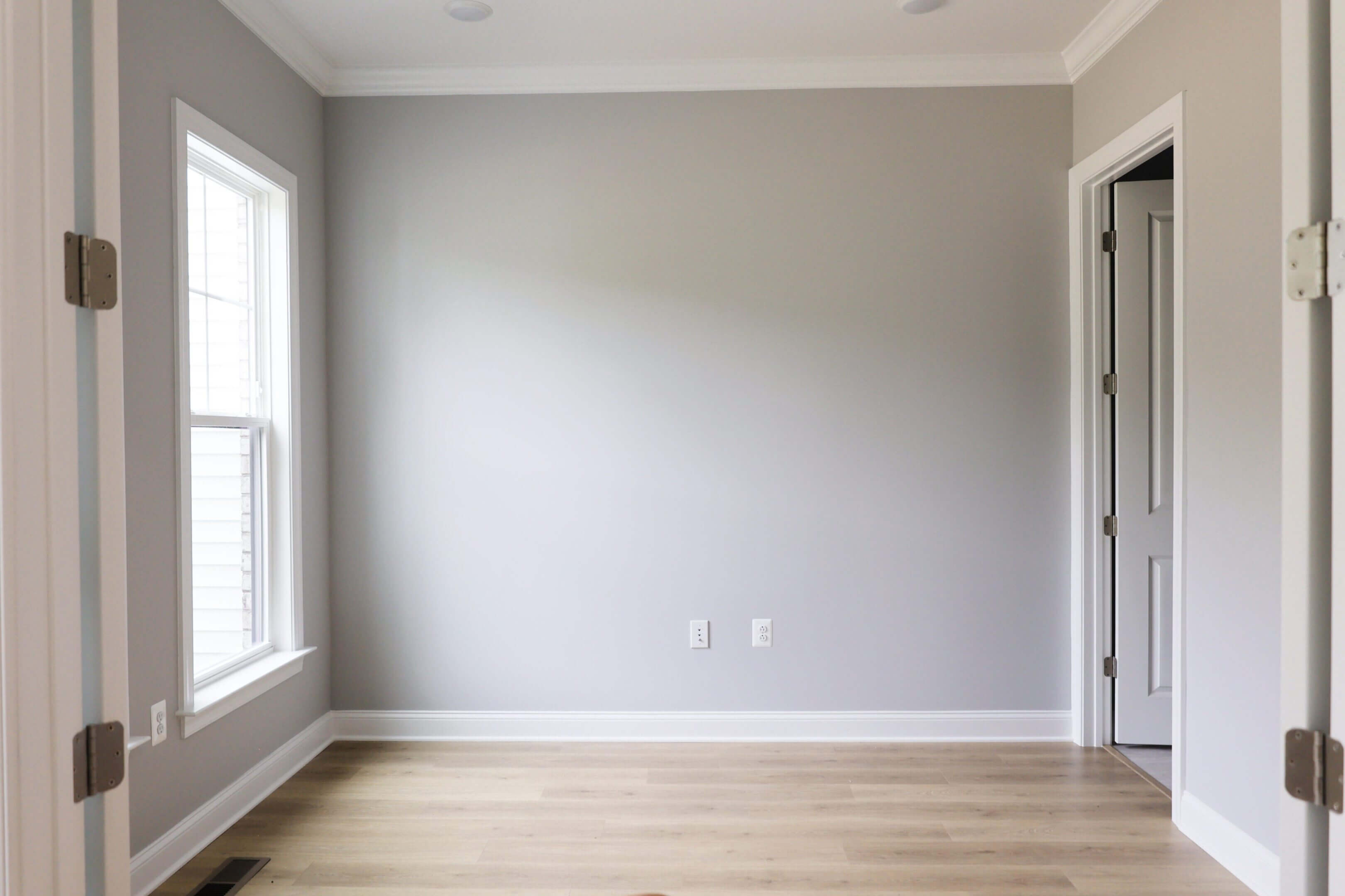 Empty room with light gray walls and wooden floor.