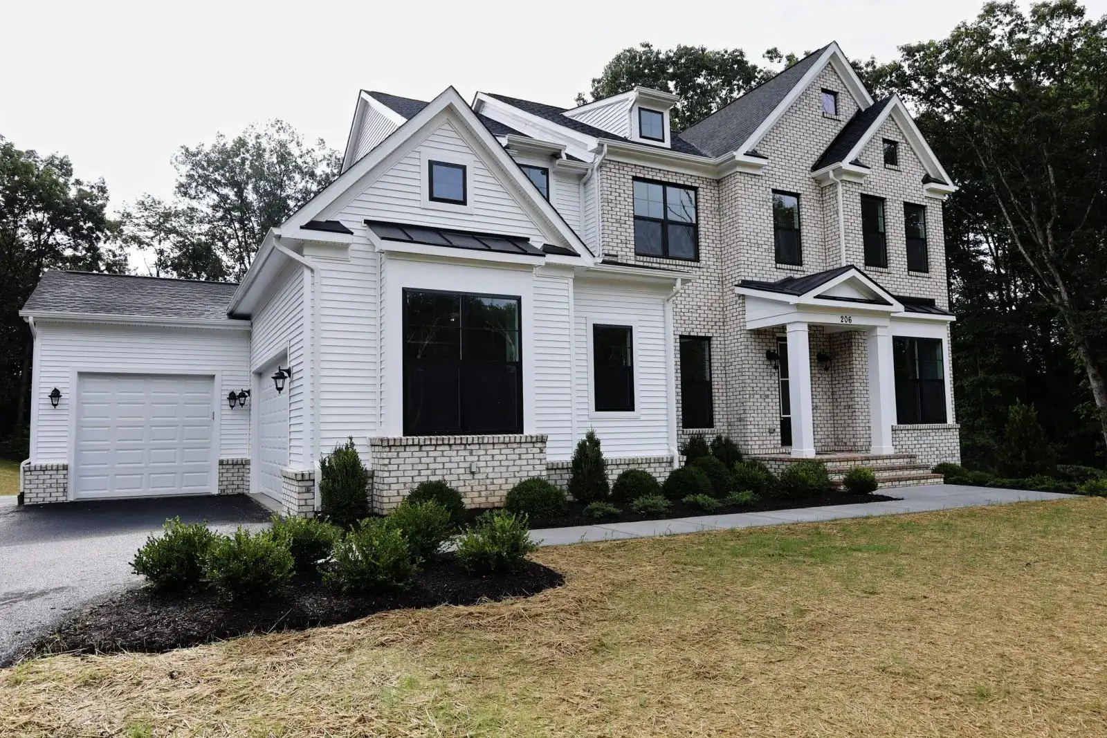 A large modern white house with black-trimmed windows and a well-maintained lawn.
