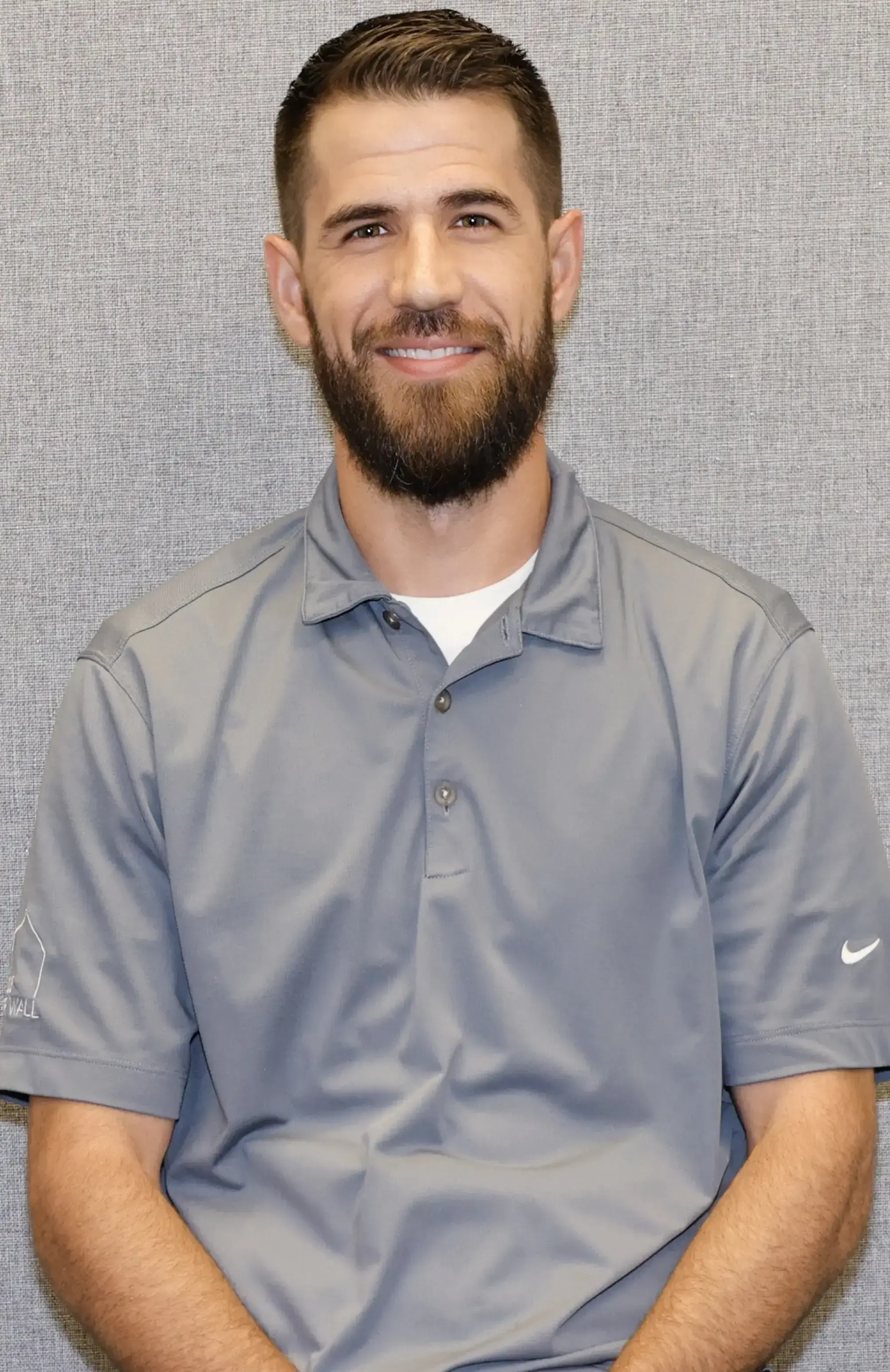 Smiling man with beard wearing a gray Nike polo shirt.